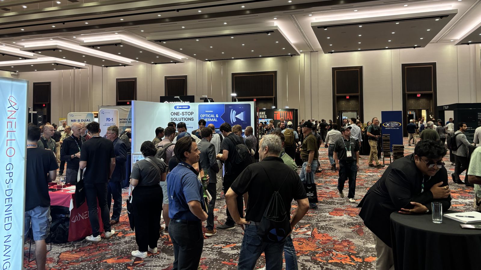 Attendees speaking with exhibitors inside the crowded Commercial UAV Expo exhibition hall.
