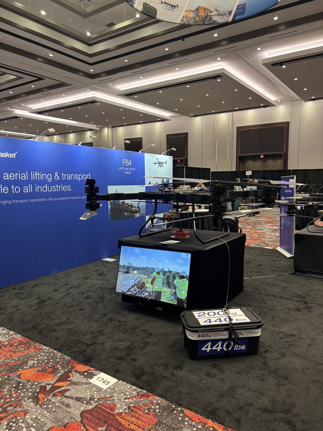 Heavy-lift multicopter displayed beside a 440-pound cargo demonstration at Commercial UAV Expo.